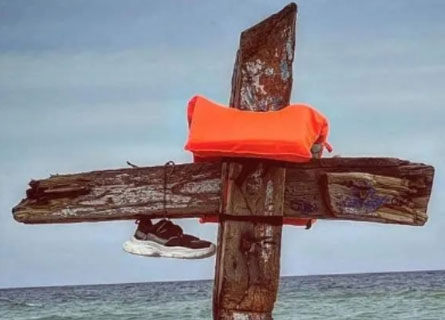 Una croce con i resti del barcone naufragato a Cutro